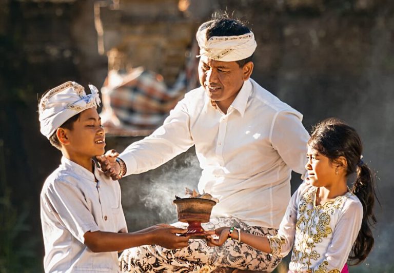 Ayah dan dua anak berpakaian adat Bali.