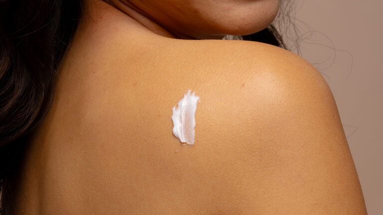 seorang wanita mengaplikasikan krim pada punggung