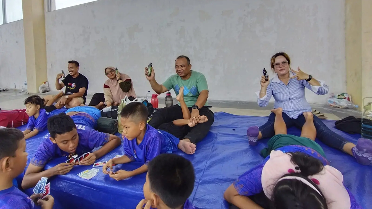 Orang tua membalurkan Minyak Kutus Kutus untuk menjaga otot anak-anak tetap hangat sebelum mengikuti kompetisi renang.