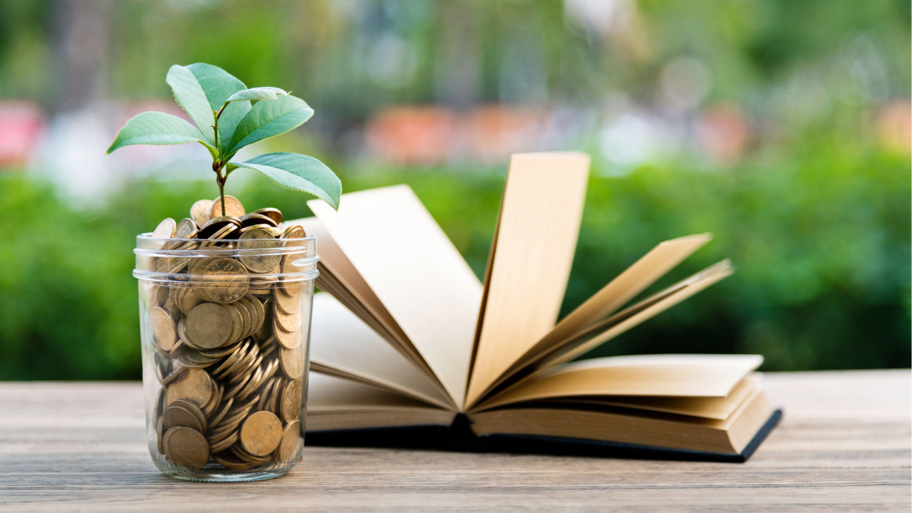 Coins with a growing plant beside an open book