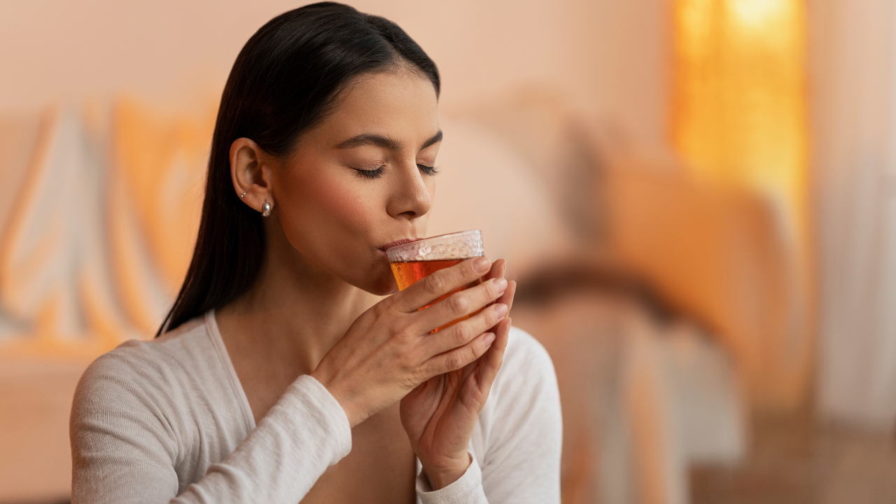 Woman enjoying a warm cup of herbal tea in a cozy indoor setting with soft lighting.